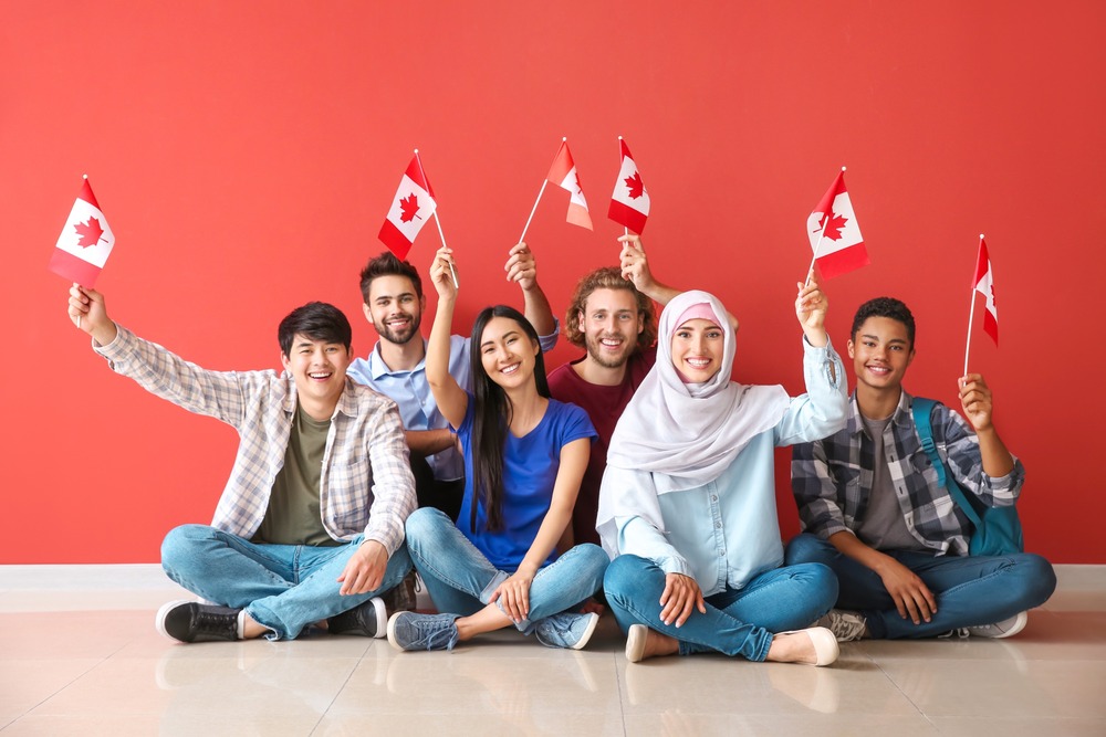 grupo de jovenes estudiantes posa ondeando banderas de canada