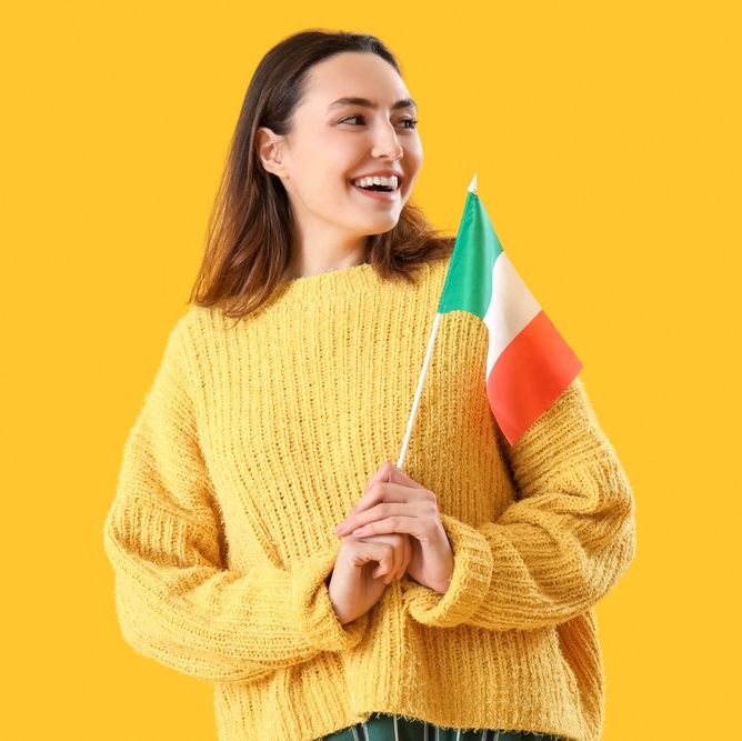 estudiante sonriente con jersy amarillo sostiene bandera de irlanda